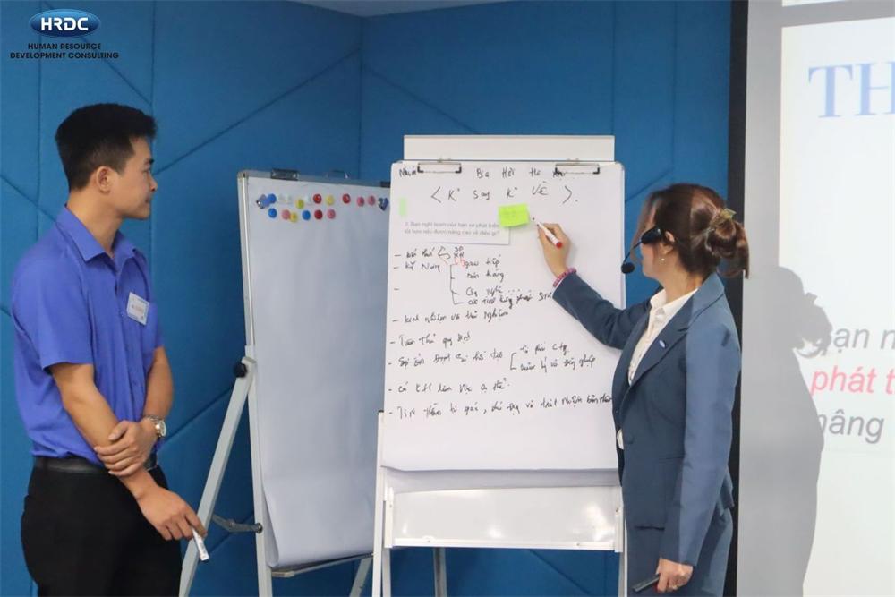 Giảng viên hướng dẫn học viên trên flipchart